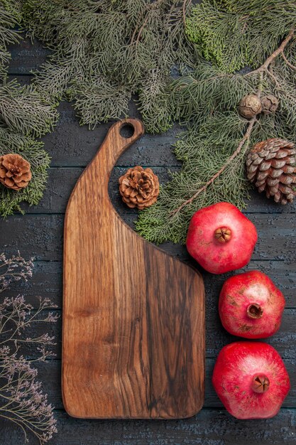 Bovenaanzicht van veraf bord en granaatappels rijpe granaatappels naast keukenbord en takken met kegels