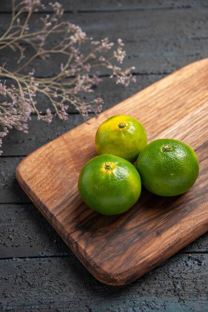 Bovenaanzicht van veraf drie limoenen drie limoenen op keukenbord op tafel naast de takken