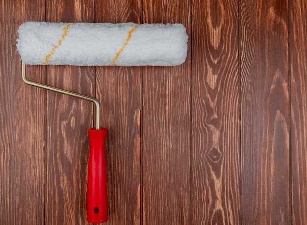 Bovenaanzicht van verfroller op houten achtergrond met kopie ruimte