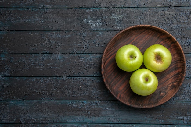 Bovenaanzicht van verre kom appels bruine kom smakelijke groene appels aan de rechterkant van donkere tafel