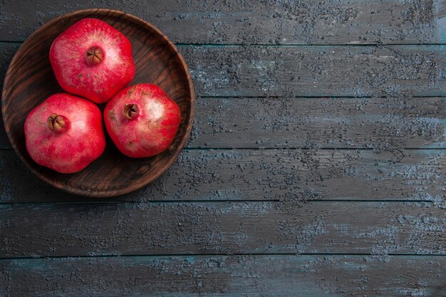 Bovenaanzicht van verre kom met granaatappels kom met rijpe rode granaatappels aan de linkerkant van tafel