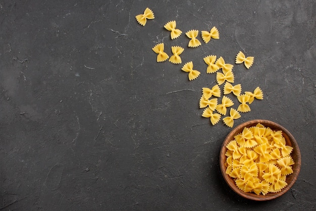 Bovenaanzicht van verre pasta in kom houten kom smakelijke pasta aan de rechterkant van de donkere tafel