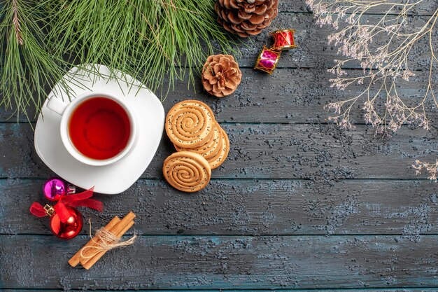 Bovenaanzicht van verre theespar met kegels en kerstspeelgoed, kaneelstokjes en een kopje thee op de schotel