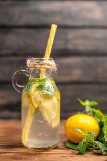 Bovenaanzicht van vers detoxwater geserveerd met tube mint en sinaasappel op een bruine achtergrond