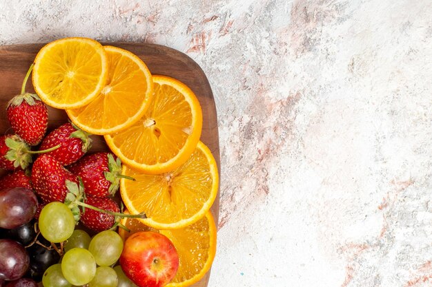 Bovenaanzicht van vers fruit samenstelling sinaasappelen druiven en aardbeien op witte ondergrond