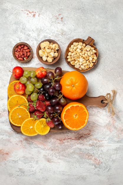 Bovenaanzicht van vers fruit samenstelling verse sinaasappelen druiven noten en aardbeien op witte ondergrond