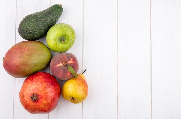 Bovenaanzicht van vers fruit zoals mango peer appel granaatappel op wit met kopie ruimte