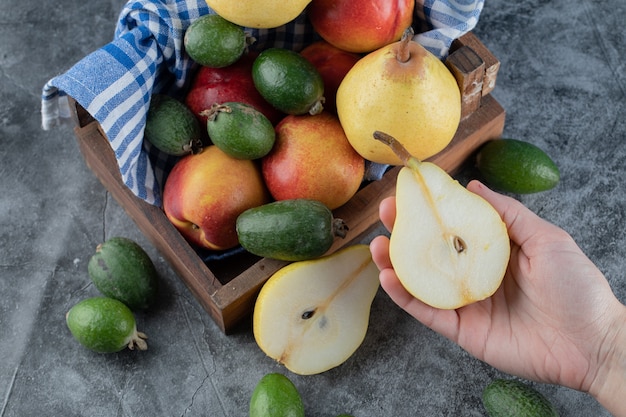 Bovenaanzicht van vers fruitmand. Vrouw met half gesneden peer.