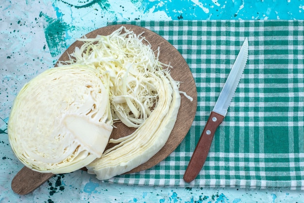 Bovenaanzicht van vers gesneden kool in stukjes gesneden en half geheel op helderblauw bureau, plantaardige snack gezonde salade