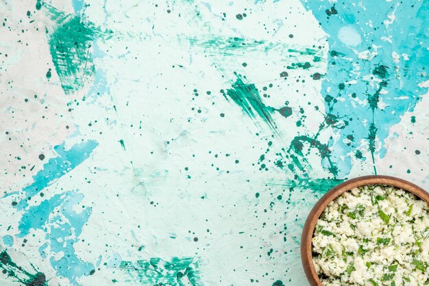 Bovenaanzicht van vers gesneden koolsalade met greens in bruine kom op helderblauwe, groene snack van de voedselsalade