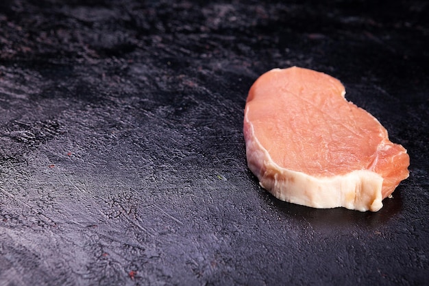 Bovenaanzicht van vers rauw vlees op op zwarte houten tafel. Gastronomisch eten en verse ongekookte maaltijd?