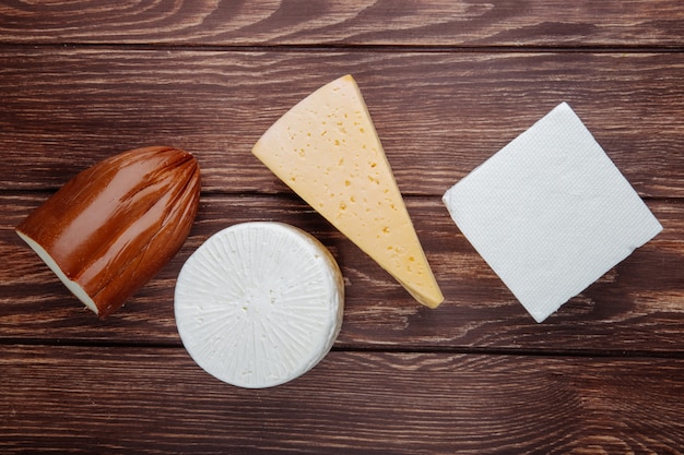 Bovenaanzicht van verschillende soorten kaas op rustieke houten tafel