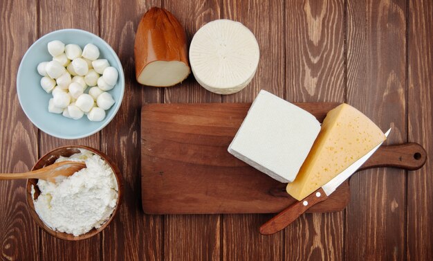 Bovenaanzicht van verschillende soorten kaas op rustieke houten tafel