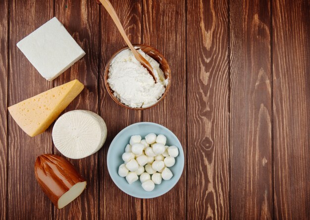 Bovenaanzicht van verschillende soorten kaas op rustieke houten tafel