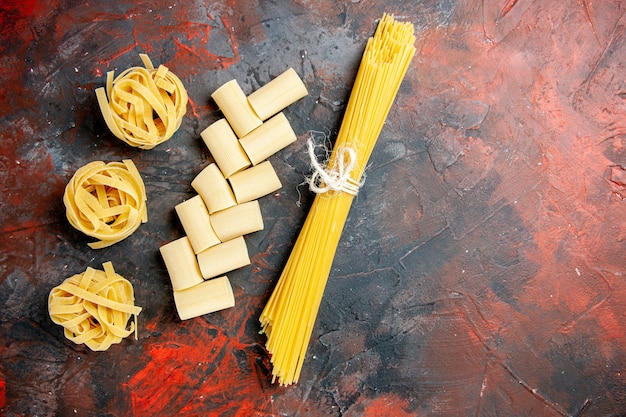 Bovenaanzicht van verschillende soorten ongekookte pasta's op zwarte achtergrond