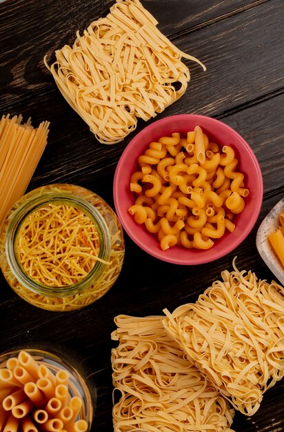 Bovenaanzicht van verschillende soorten pasta als bucatini cavatappi spaghetti vermicelli tagliatelle en anderen op houten oppervlak