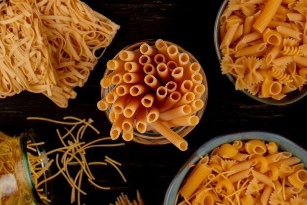 Bovenaanzicht van verschillende soorten pasta als bucatini spaghetti tagliatelle en anderen op houten oppervlak