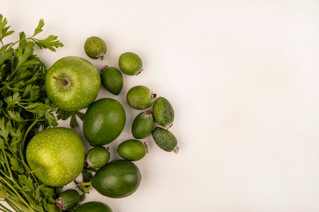 Bovenaanzicht van verse appels met limoenen feijoas en peterselie geïsoleerd op een witte muur met kopie ruimte