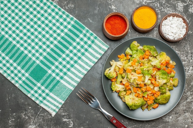 Bovenaanzicht van verse en gezonde groentesalade op groene gestripte handdoek op grijze tafel