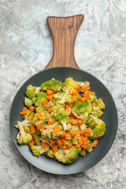 Bovenaanzicht van verse en gezonde groentesalade op houten snijplank op witte achtergrond