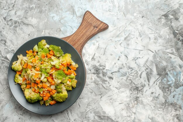 Bovenaanzicht van verse en gezonde groentesalade op houten snijplank op witte tafel