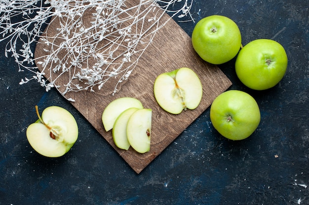 Gratis foto bovenaanzicht van verse groene appelsamenstelling met half gesneden gesneden één bekleed op donker bureau, vers zacht rijp fruit