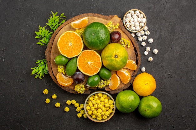 Gratis foto bovenaanzicht van verse groene mandarijnen met feijoa's en snoepjes op dark