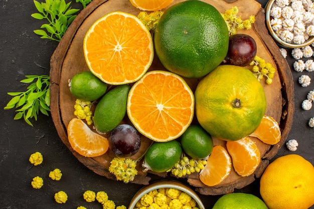 Gratis foto bovenaanzicht van verse groene mandarijnen met feijoa's en snoepjes op dark