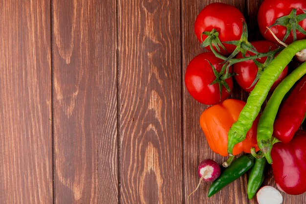bovenaanzicht van verse groenten, rijpe tomaten, groene chili pepers, kleurrijke paprika en radijs op houten rustieke achtergrond met kopie ruimte