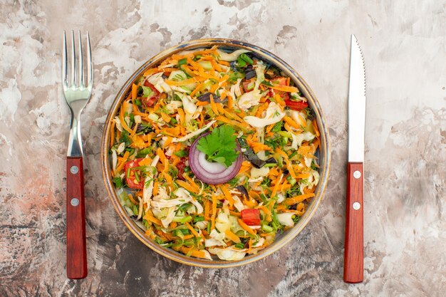 Bovenaanzicht van verse heerlijke veganistische salade van verschillende biologische groenten geserveerd met mes en vork