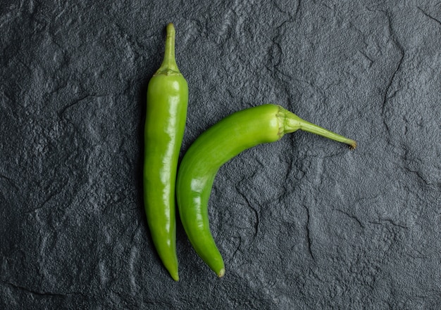 Bovenaanzicht van verse hete pepers op zwarte achtergrond.