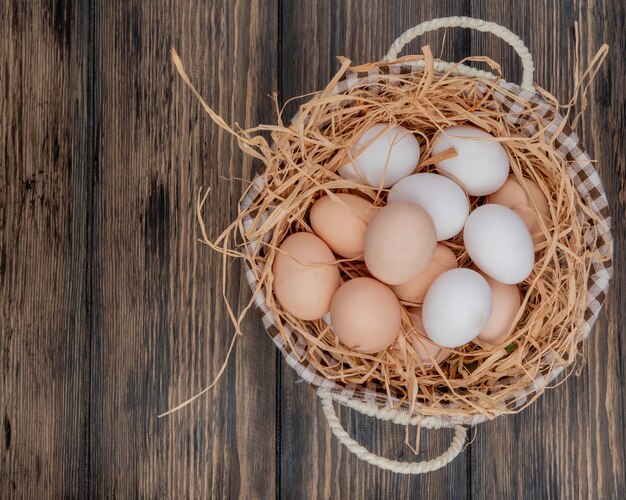 Bovenaanzicht van verse kippeneieren op nest op een emmer op een houten achtergrond met kopie ruimte