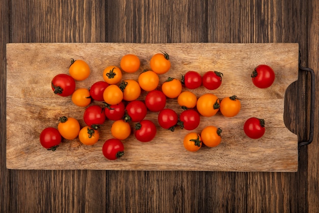 Bovenaanzicht van verse kleurrijke kerstomaatjes geïsoleerd op een houten keukenbord op een houten muur