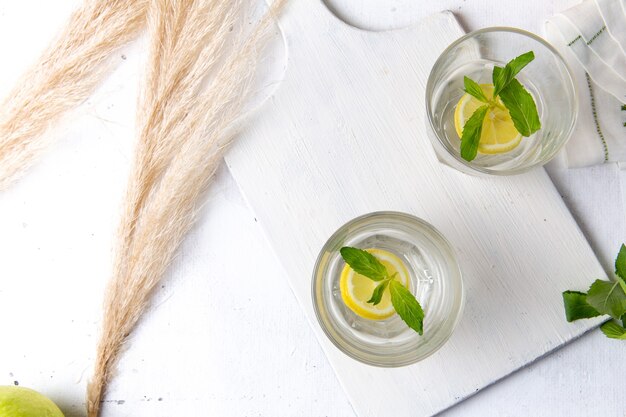 Bovenaanzicht van verse koele limonade met gesneden citroenen in glazen op het witte oppervlak