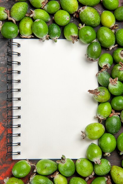 Gratis foto bovenaanzicht van verse natuurlijke groene feijoas kleine vitaminebom en notebook