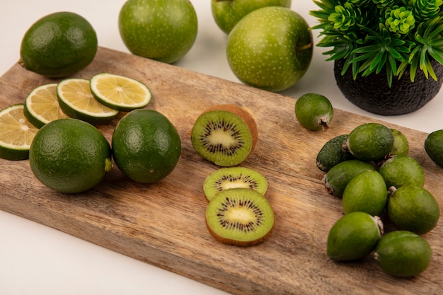 Bovenaanzicht van verse plakjes limoenen (lemmetjes) op een houten keukenbord met kiwi feijoa en groene appels geïsoleerd op een witte achtergrond