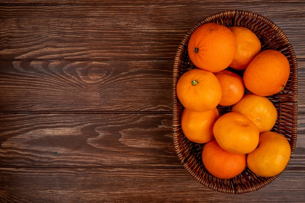 Bovenaanzicht van verse rijpe mandarijnen in een rieten mand op hout met kopie ruimte