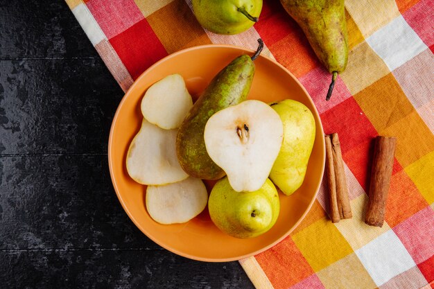 Bovenaanzicht van verse rijpe peren en plakjes peren op een plaat