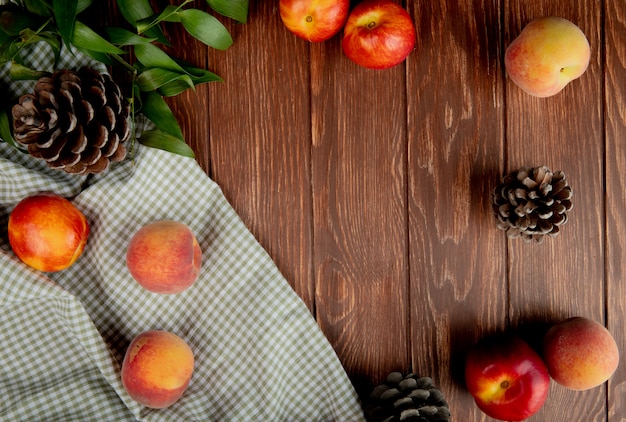Bovenaanzicht van verse rijpe vruchten nectarine en perzik met kegels op geruite stof op houten rustieke tafel