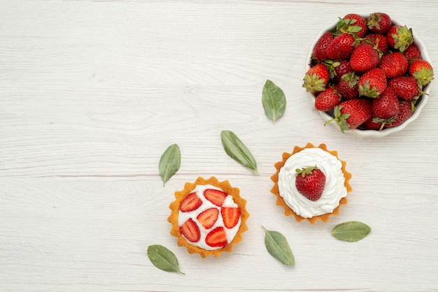 Bovenaanzicht van verse rode aardbeien zachte en heerlijke bessen in witte plaat met gebak op licht, fruit berry rood