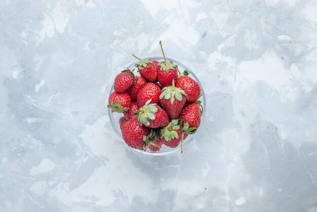 Bovenaanzicht van verse rode aardbeien, zachte zomerbessen in glazen plaat op licht bureau, bessenfruit mellow vitamine