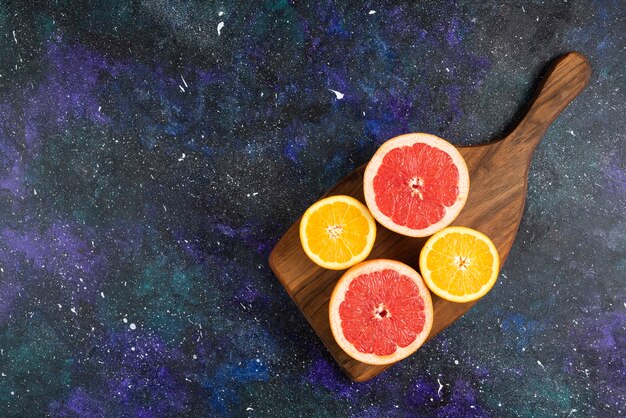 Bovenaanzicht van verse sinaasappel- en grapefruitschijfjes op een houten bord.