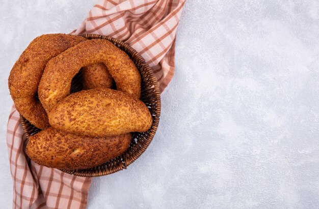 Bovenaanzicht van verse Turkse bagels op een emmer op een gecontroleerde doek op een witte achtergrond met kopie ruimte