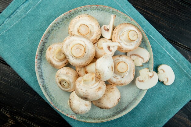 Bovenaanzicht van verse witte champignons op een blauw bord op donkere houten oppervlak