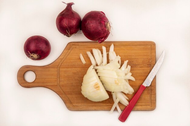 Bovenaanzicht van verse witte ui op een houten keukenbord met mes met rode uien geïsoleerd op een wit oppervlak