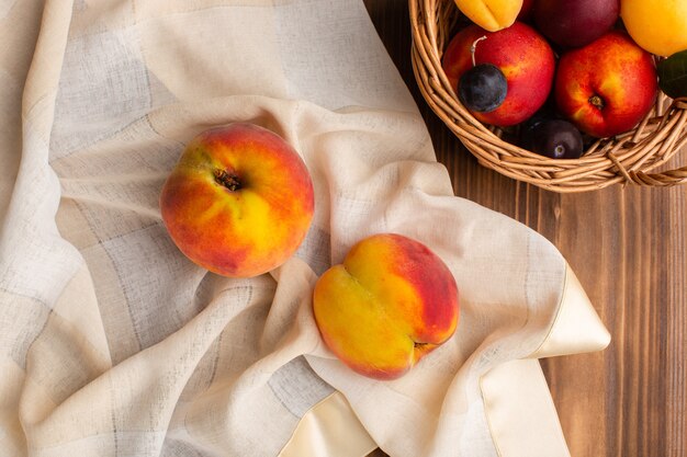 Bovenaanzicht van verse zachte perziken samen met fruit in een mand