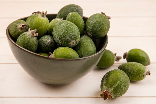 Bovenaanzicht van verse zoete aromatische feijoa op een kom op een witte houten ondergrond