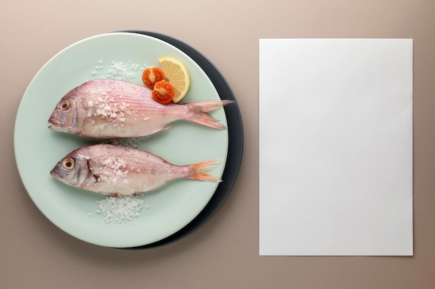 Gratis foto bovenaanzicht van vis op plaat met tomaten en papier
