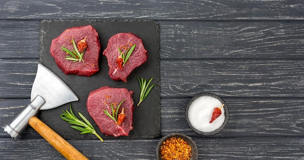 Gratis foto bovenaanzicht van vlees op leisteen met kruiden