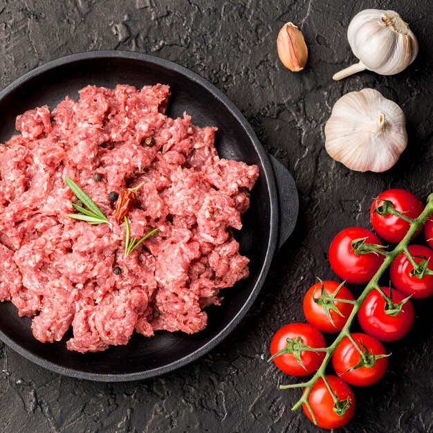 Bovenaanzicht van vlees op plaat met knoflook en tomaten
